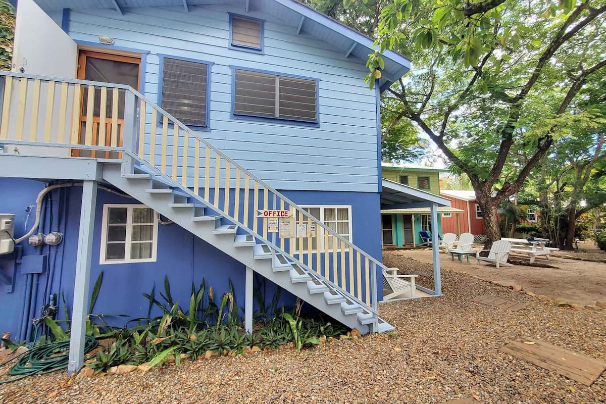A two-story building with a blue exterior, a staircase leading to the upper floor, and a small porch area with outdoor seating.