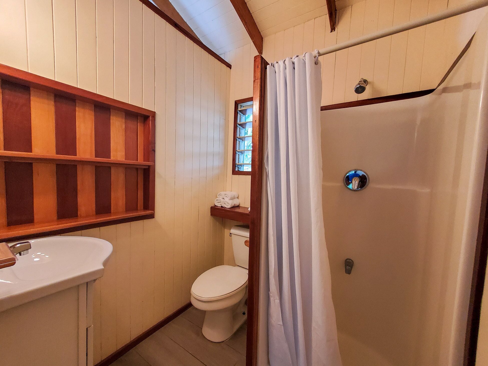A bathroom with a wooden vanity, a toilet, and a shower with a curtain.