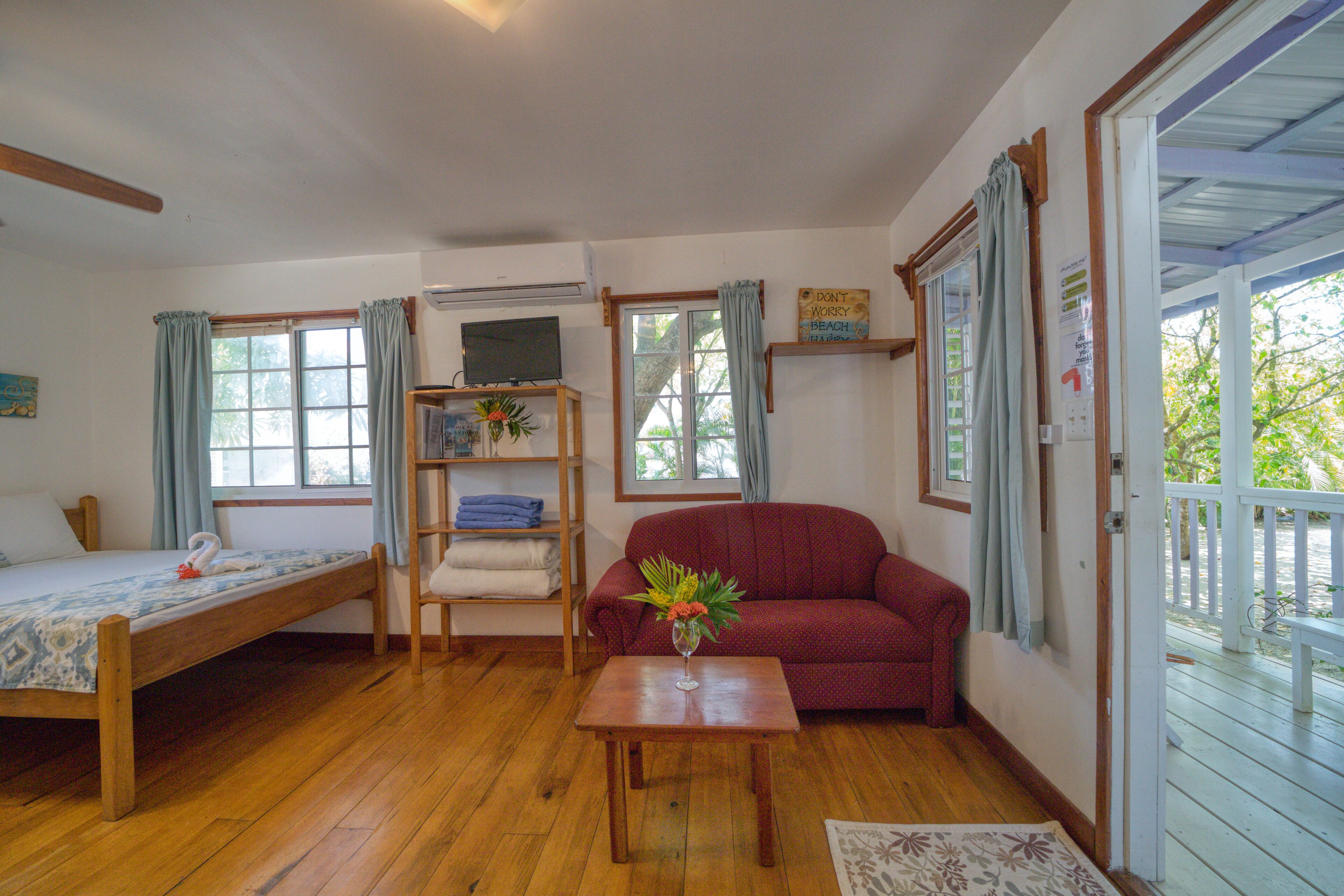 Una habitación acogedora con una cama de madera, un sofá rojo y una mesita con un florero.