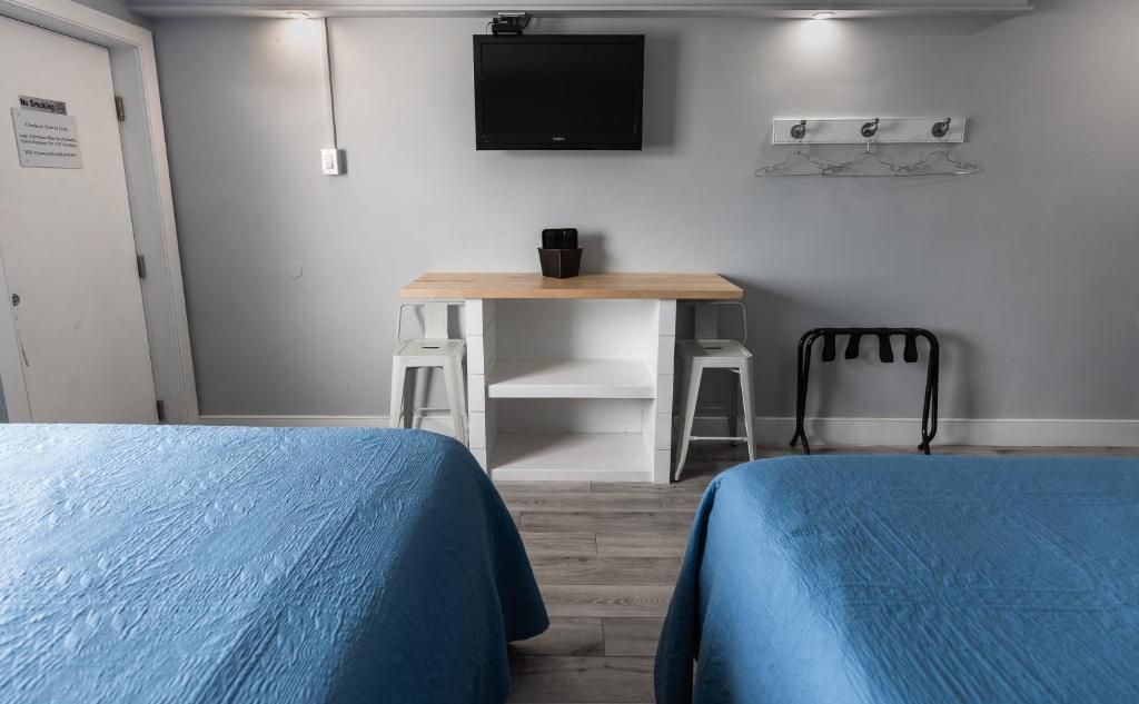 A room with two beds, a desk, a chair, a TV, and a coat rack.