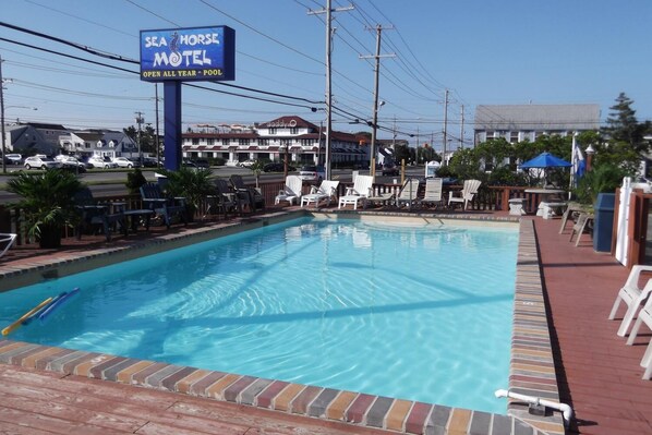 A pool area with lounge chairs and a sign for the Sea Horse Motel.