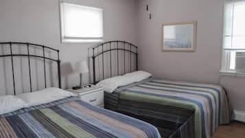 A bedroom with two single beds, a nightstand, a lamp, and a framed picture on the wall.