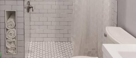 Une salle de bain avec douche, toilettes et lavabo.