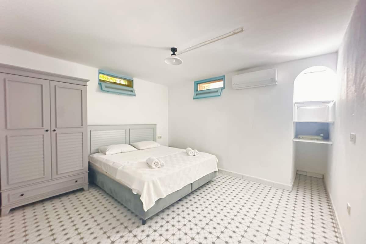 A bedroom with a bed, wardrobe, and a window.
