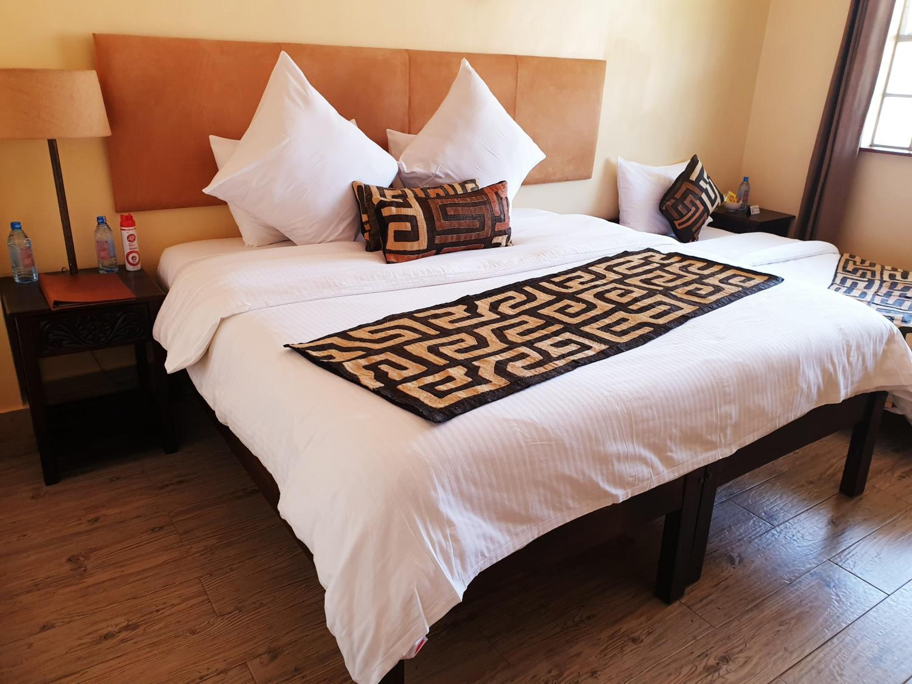 A neatly made bed with white linens, a patterned throw, and a headboard.