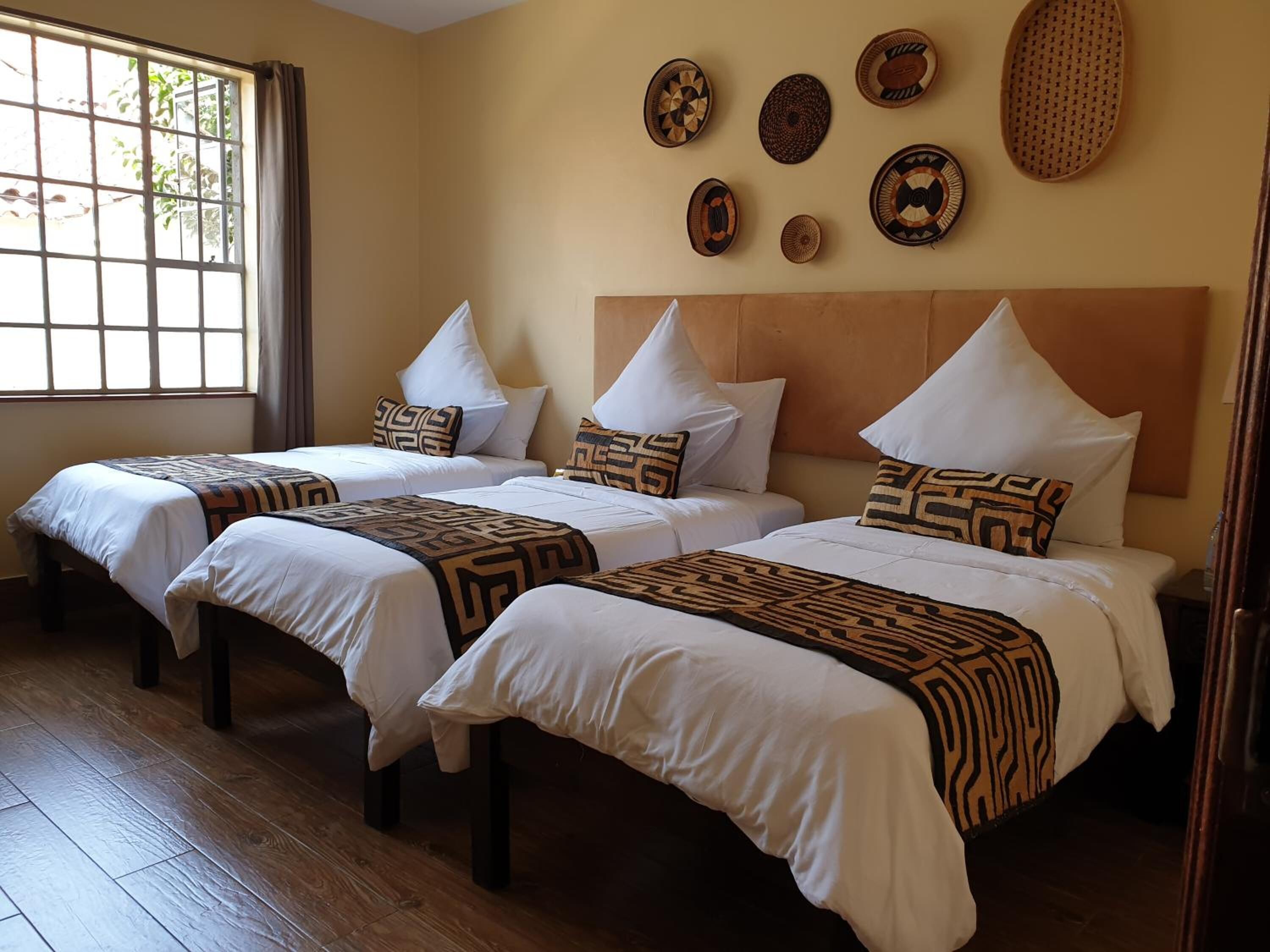 Habitación de hotel con dos camas, un ventanal grande y decoración en la pared.
