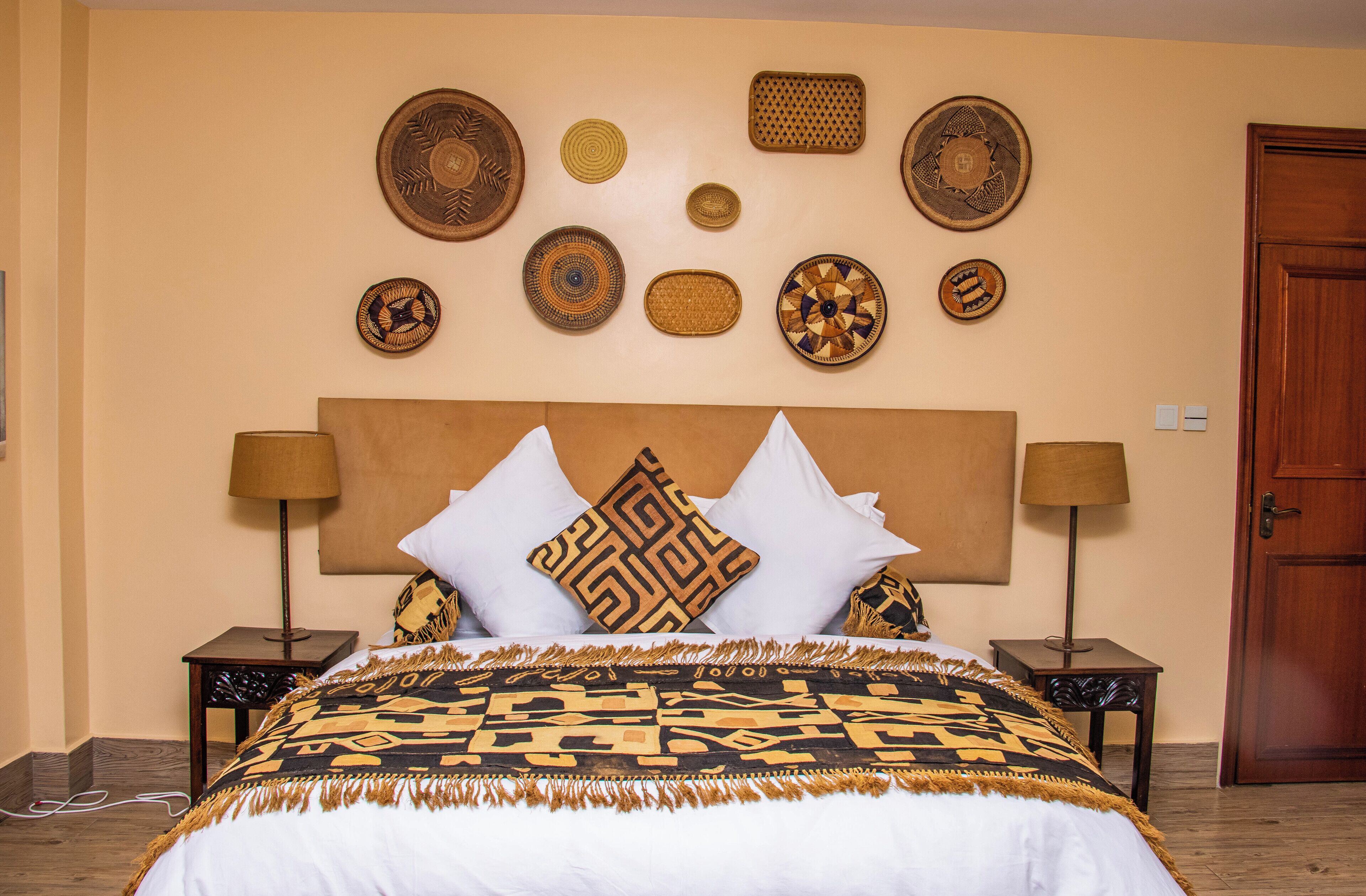 A neatly arranged bedroom with a large bed, two bedside tables, a wooden door, and decorative wall art.