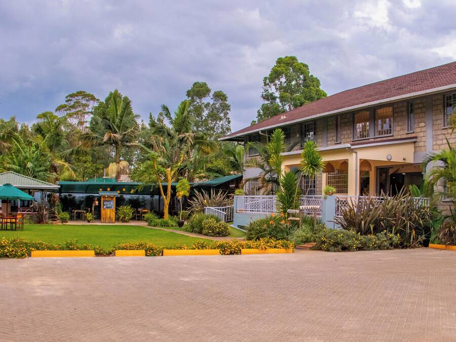 A hotel with a reception area, outdoor seating, and lush landscaping.