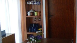 A wooden dining table with a vase of flowers, a hanging light fixture, and a wooden door in the background. - Triplex Nro 2 Costa Atlantica Argentina (San Bernardo del Tuyú)