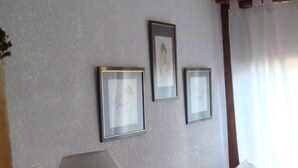 A bedroom with a bed, a bedside table with a lamp, and three framed pictures on the wall. - Triplex Nro 2 Costa Atlantica Argentina (San Bernardo del Tuyú)