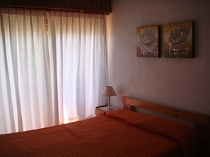 A bedroom with a bed, a nightstand, a lamp, and two wall art pieces.