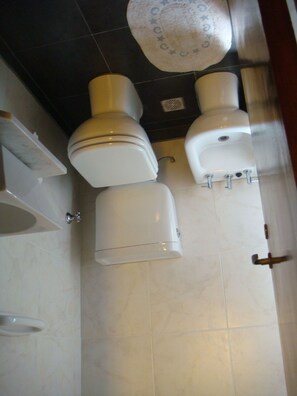A bathroom with a toilet, sink, and a mirror.