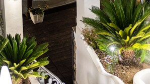 Espaço interior moderno com um banco branco curvo, escada de metal e plantas em vasos.