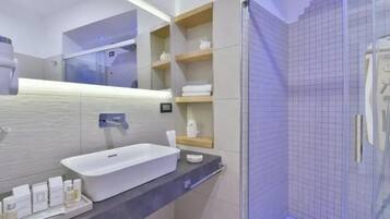 Un bagno moderno con un ampio lavandino bianco, uno specchio e un box doccia in vetro.