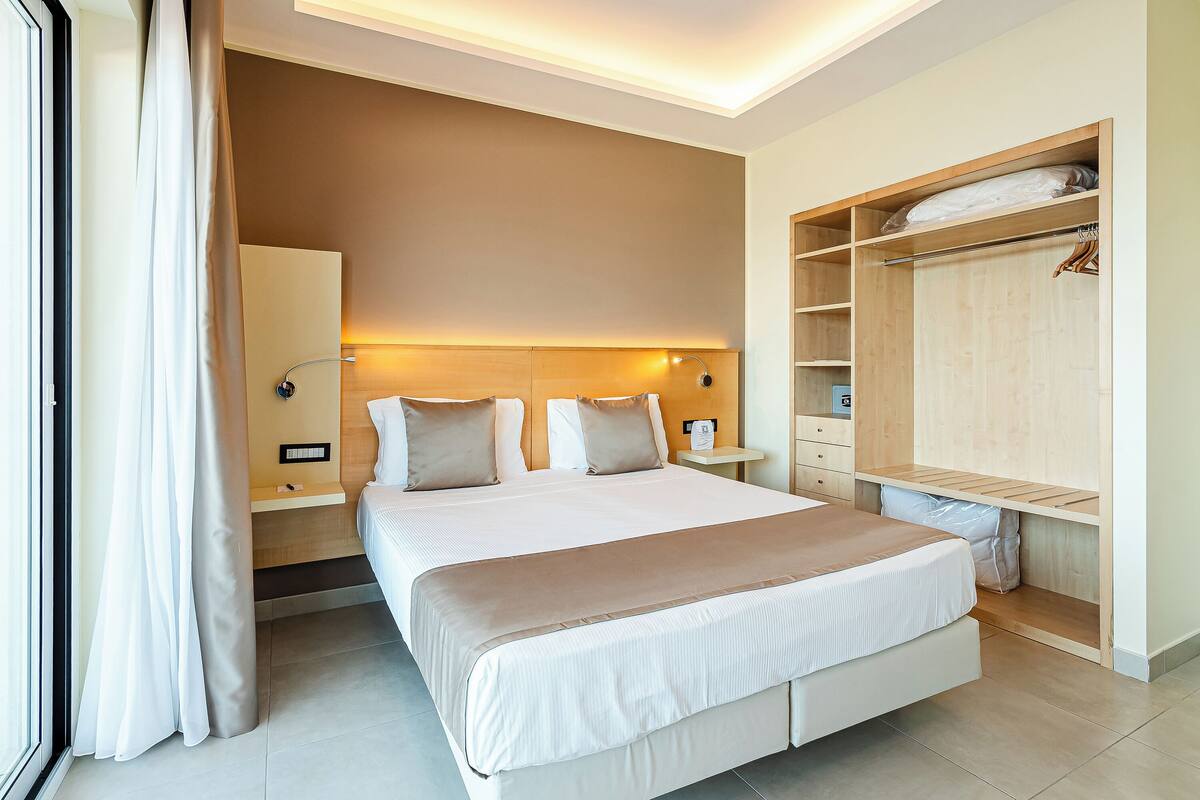 Ein Hotelzimmer mit einem großen Bett, Nachttischen, einem Kleiderschrank und einem Beistelltisch.