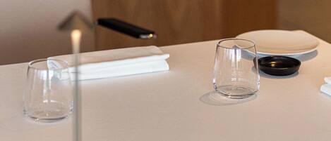 A table with a clear glass, a black ashtray, and a white napkin.