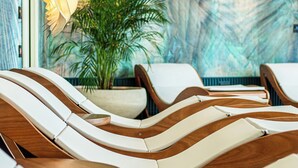Uma área de spa com espreguiçadeiras de madeira e uma grande planta em vaso.