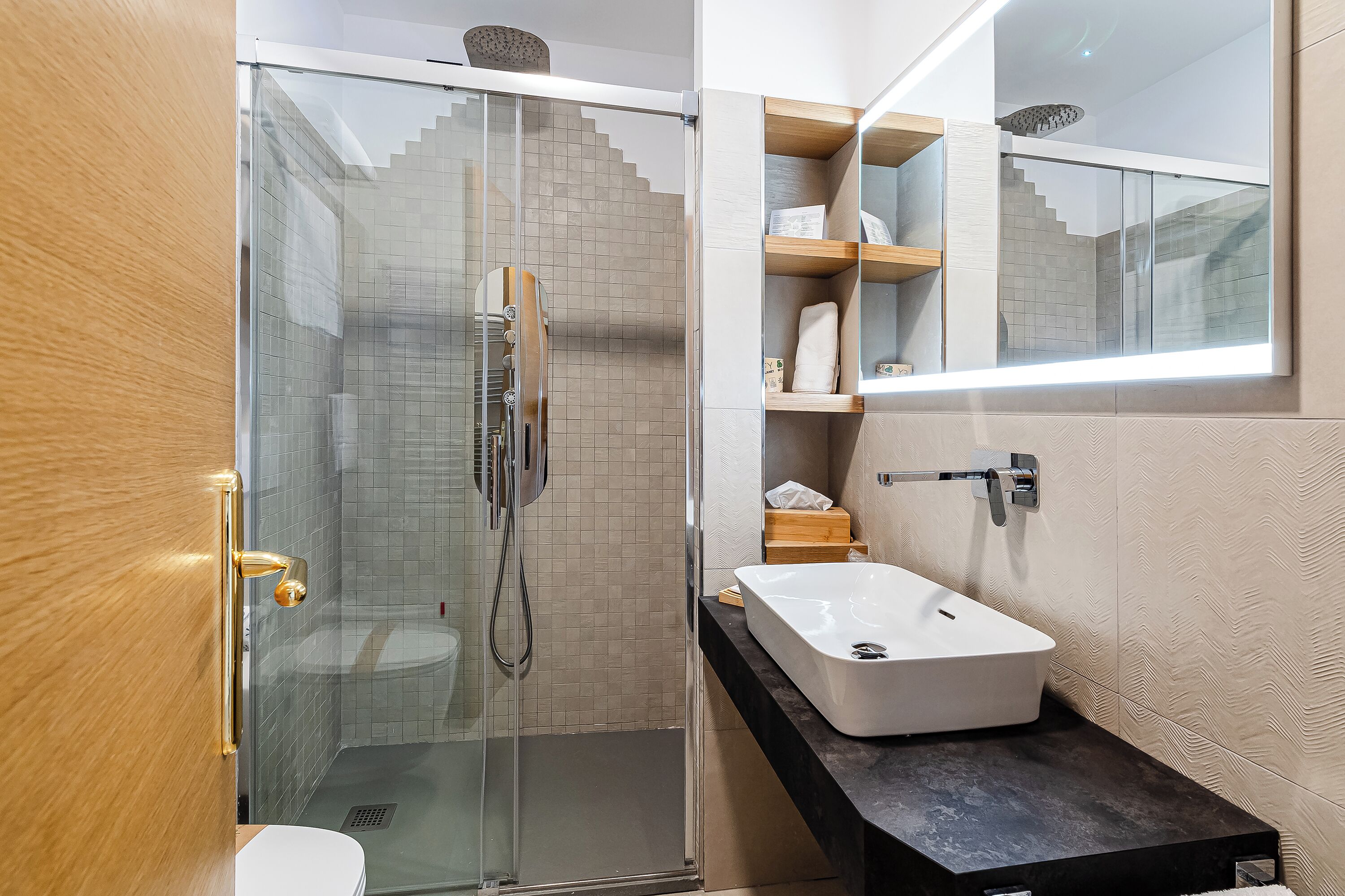 A modern bathroom with a glass shower enclosure, a white sink, and a wooden vanity.