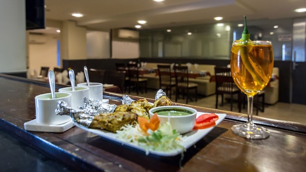 A restaurant setting with a table set for a meal, including a plate of food, a glass of drink, and condiments. - The Central Park (Hyderabad)