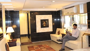 A hotel lobby with a sofa, a lamp, a Buddha statue, and an air conditioning unit. - The Central Park (Hyderabad)