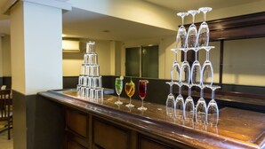 A bar area with a stack of wine glasses and a variety of drinks on the counter. - The Central Park (Hyderabad)