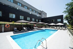Piscina a l'aire lliure de temporada, para-sols i gandules