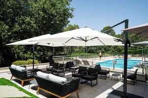 Una piscina al aire libre de temporada, sombrillas, tumbonas