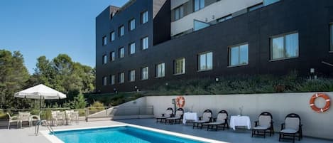 Una piscina al aire libre de temporada, sombrillas