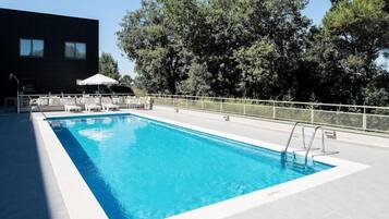 Una piscina al aire libre de temporada, sombrillas, tumbonas