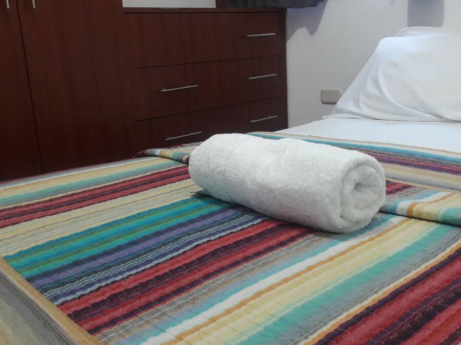 Ein Hotelzimmer mit einem Bett, einer gestreiften Decke und einem Holzschrank.