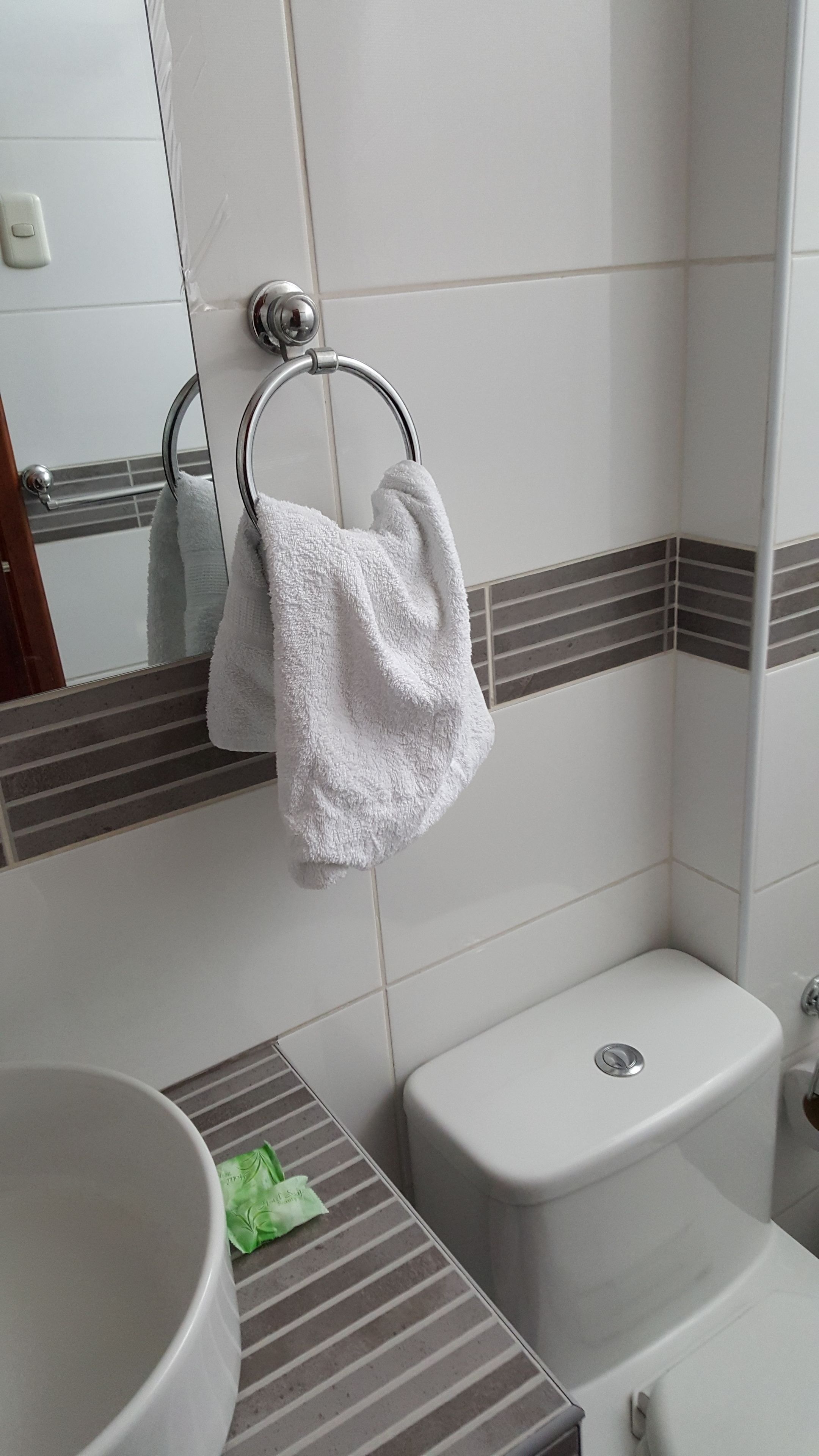 Une salle de bain comprenant des toilettes, un lavabo et un porte-serviettes avec deux serviettes.