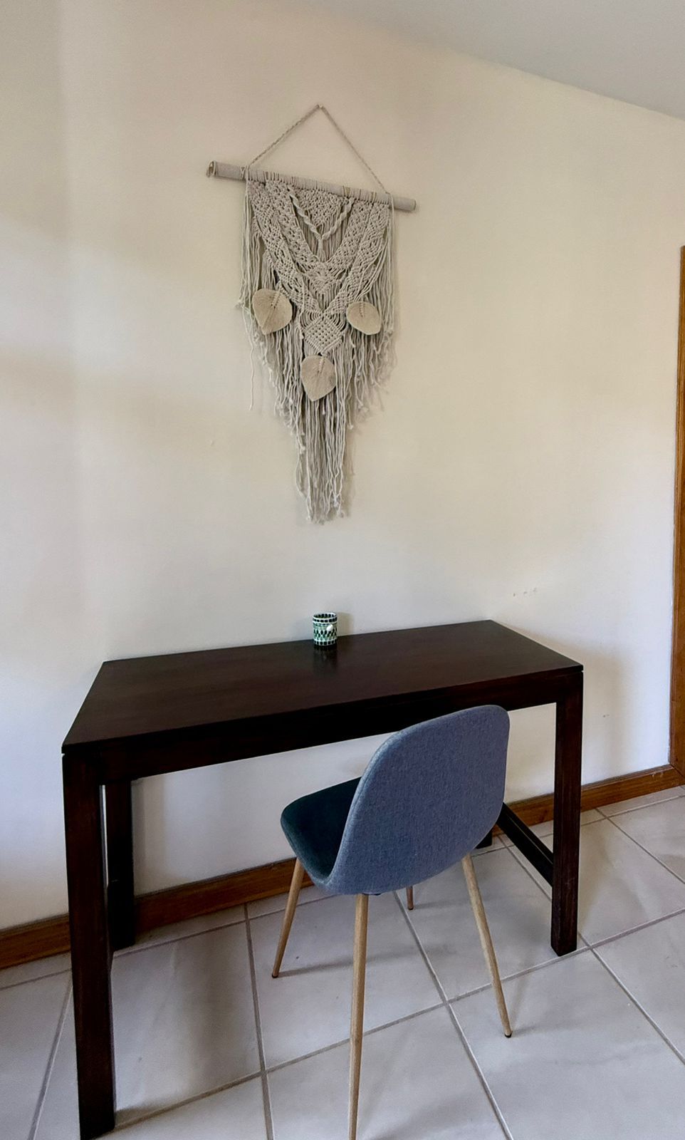 A dark wooden table with a blue chair in front.