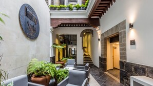 A hotel lobby with a sign reading "Boutique Dominga Santo Hotel," seating areas, potted plants, and a staircase. - Domingo Santo Hotel Boutique - Adults Only (Mexico City)