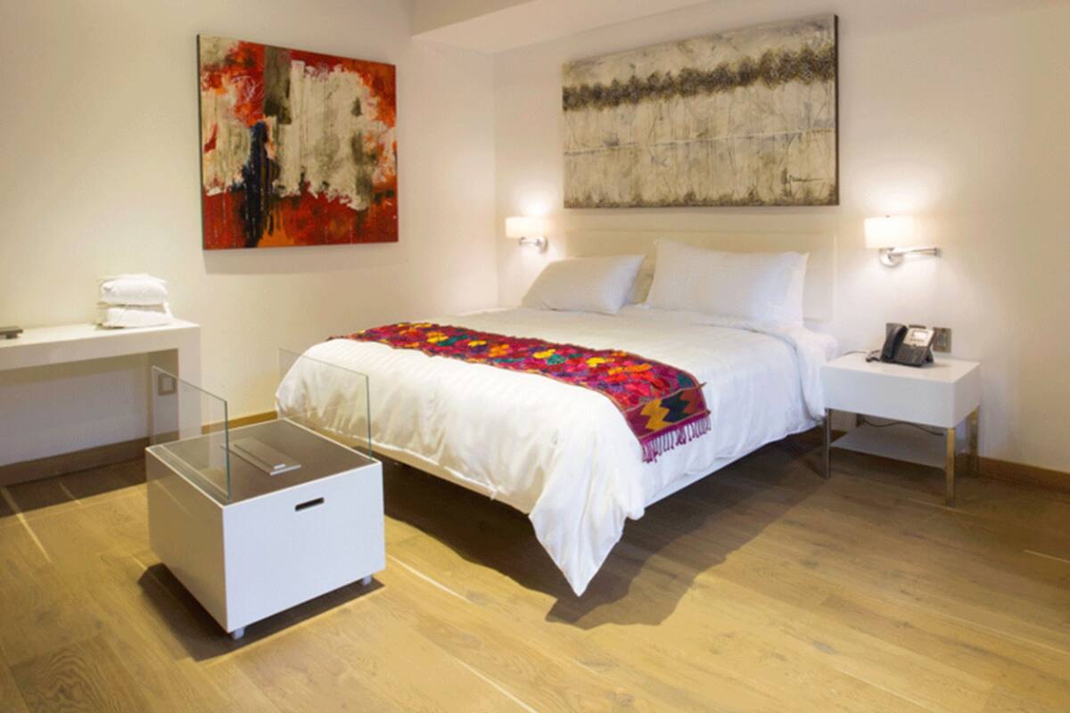 Ein modernes Hotelzimmer mit einem großen Bett, Nachttischen, einem Schreibtisch und einem Kleiderschrank.