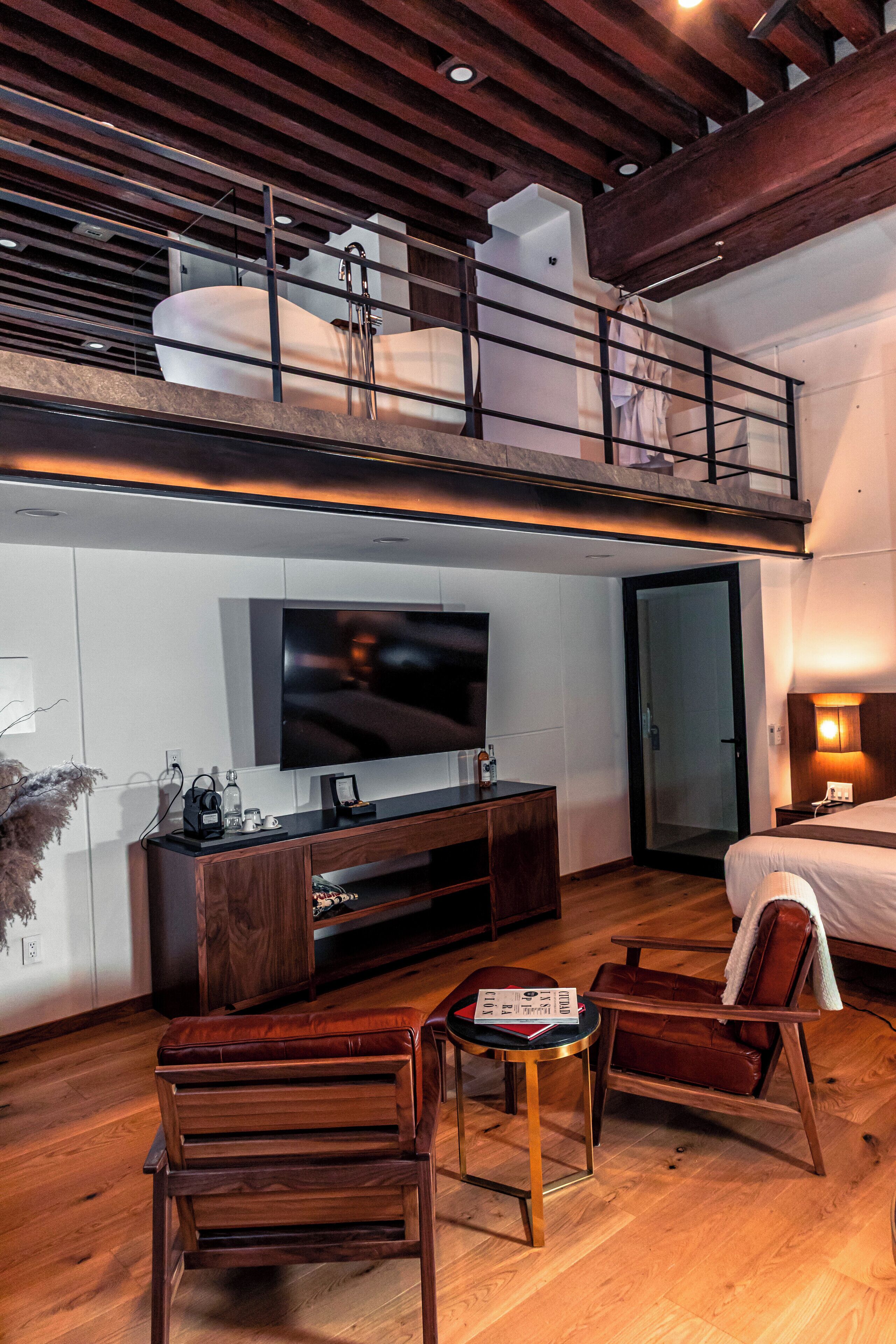 A modern loft-style room with a large TV, wooden furniture, and a balcony with a view.