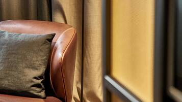 A leather armchair with a cushion, a floor lamp, and a window with curtains.