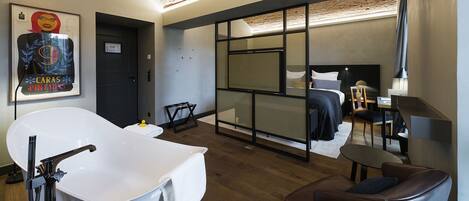 Una habitación de hotel moderna con una bañera grande, una cama con cabecera, un escritorio y una silla.