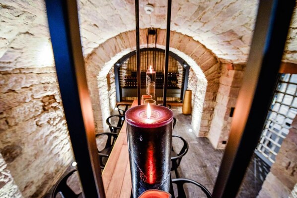 A candle in a glass holder in a room with stone walls and an arched doorway.