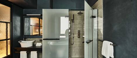 Un baño moderno con cabina de ducha de vidrio, un lavabo blanco y un espejo grande.