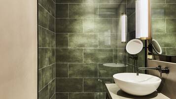 A modern bathroom with a large vessel sink, a handheld showerhead, and a wall-mounted mirror.