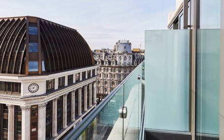 A modern building with a curved facade and a classical building with columns in the background.