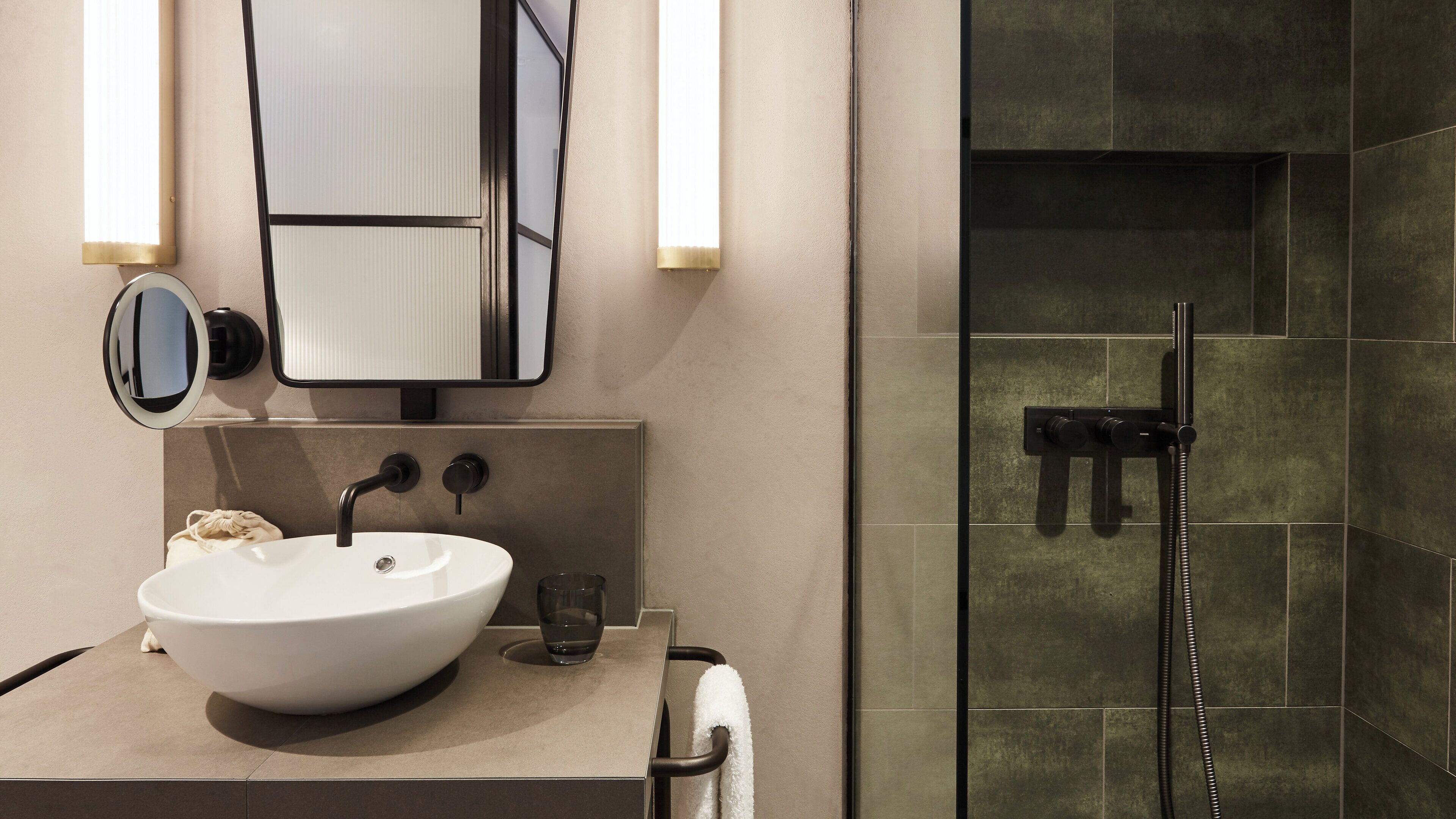 A modern bathroom with a white sink, a mirror, and a glass-enclosed shower.