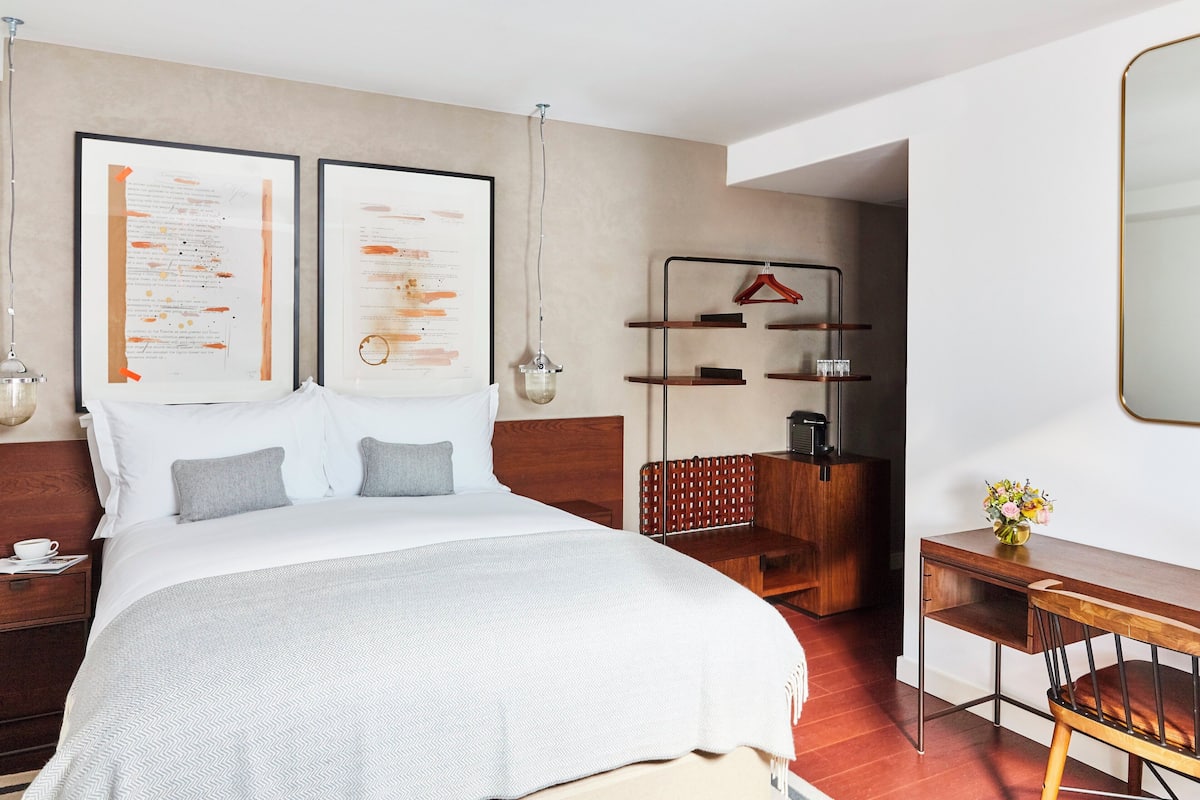Une chambre d’hôtel moderne avec un grand lit, un bureau en bois et un petit coin salon.