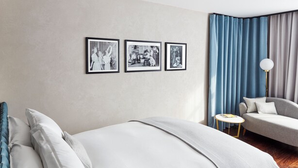 Une chambre d’hôtel avec un lit, un canapé, une petite table ronde et trois tableaux encadrés accrochés au mur.