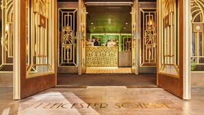 A hotel entrance with a reception desk and a sign reading "ILECESTER SQUARE".