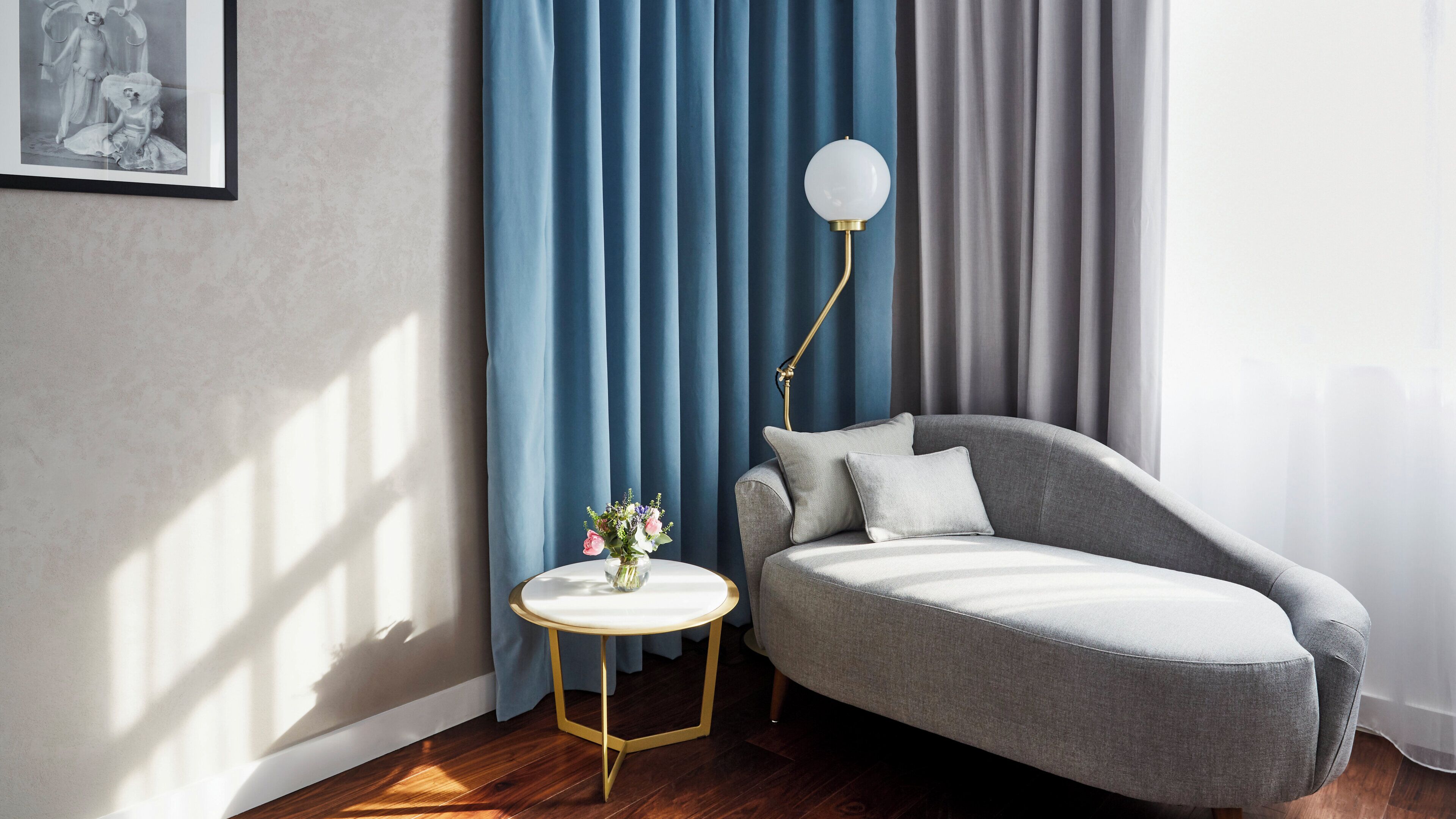Una habitación moderna con un sofá gris, una mesa redonda con un florero y una lámpara de pie.
