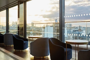Un interior moderno con mobiliario y ventanas amplias que ofrecen vistas a la ciudad.