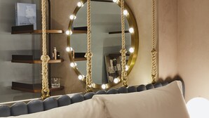 Ein Zimmer mit einem runden Spiegel mit Beleuchtung, einem Deckenventilator und einem Bücherregal mit einem Buch.