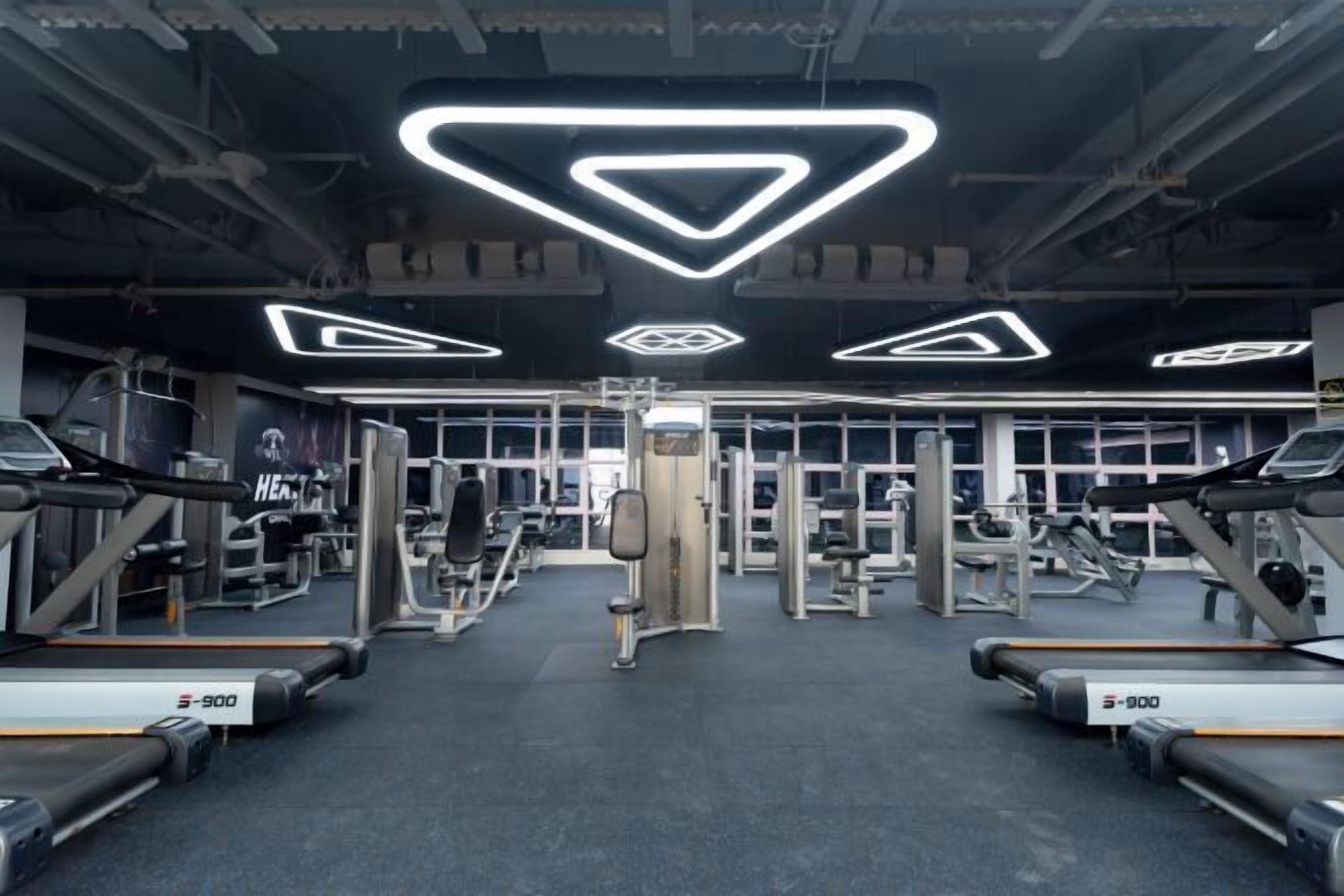 Une salle de sport équipée de tapis de course, d’appareils de musculation et de miroirs.