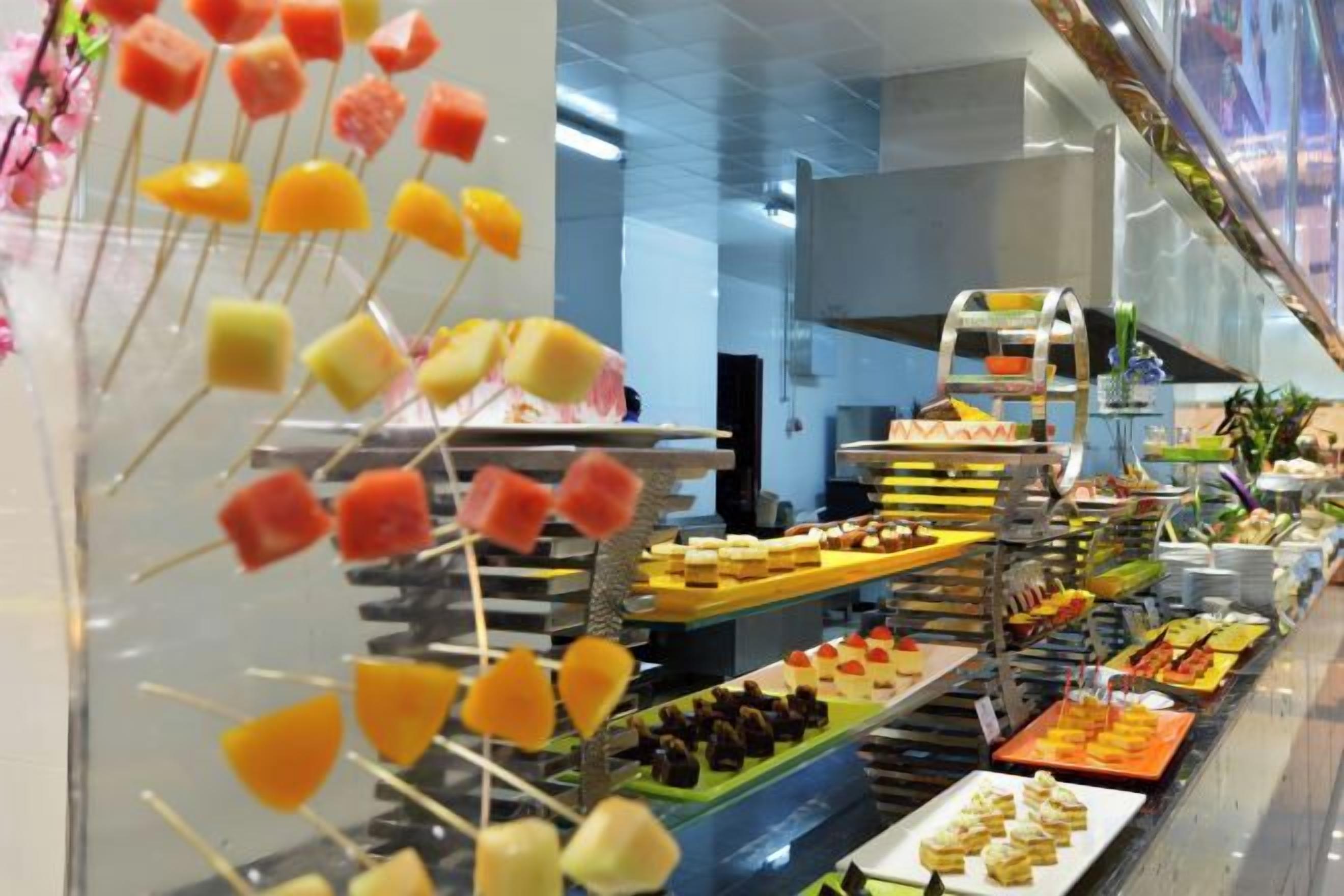 Un buffet proposant une variété de plats et agrémenté d’une présentation décorative de fruits.